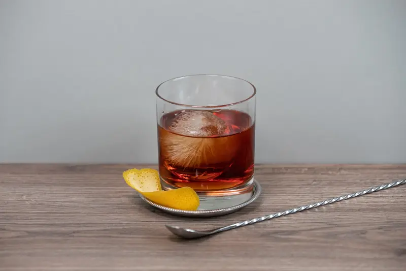 A classic whiskey cocktail with an ice sphere and citrus peel, perfect for refined settings
