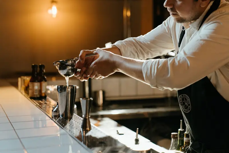 Bartender squeezing fresh lime juice into a shaker for a cocktail at a stylish bar