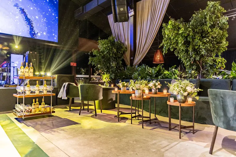 Sophisticated indoor event venue featuring lush plants, bar cart, and cozy seating arrangements