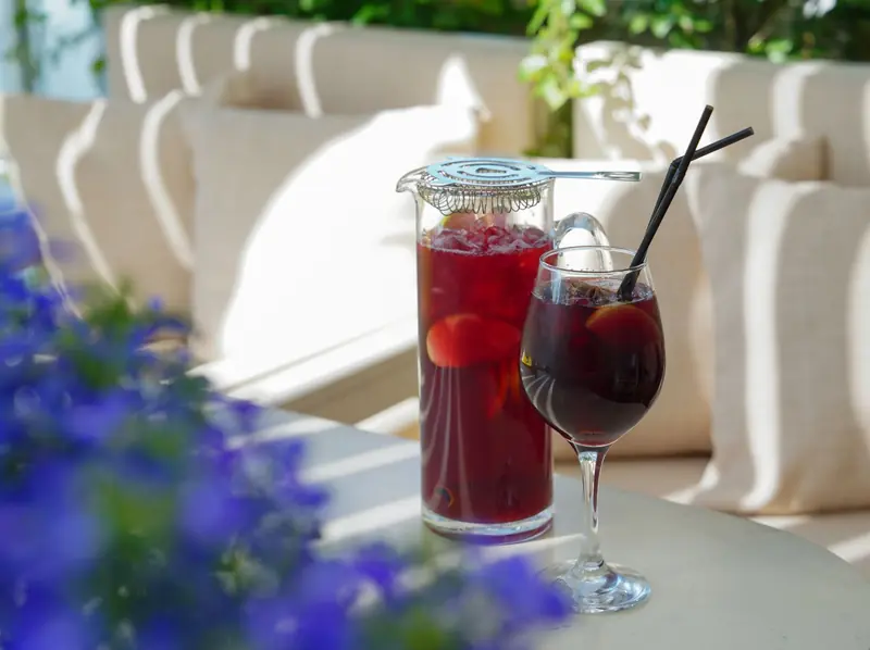 Chilled sangria in a glass and pitcher with straws on a sunny outdoor table, perfect for summer