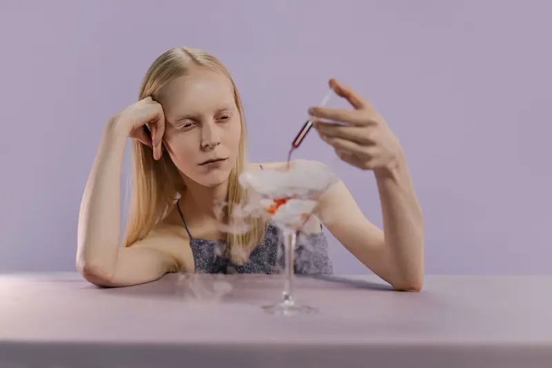 Blonde woman infusing a cocktail with a syringe. Artistic and modern light effect