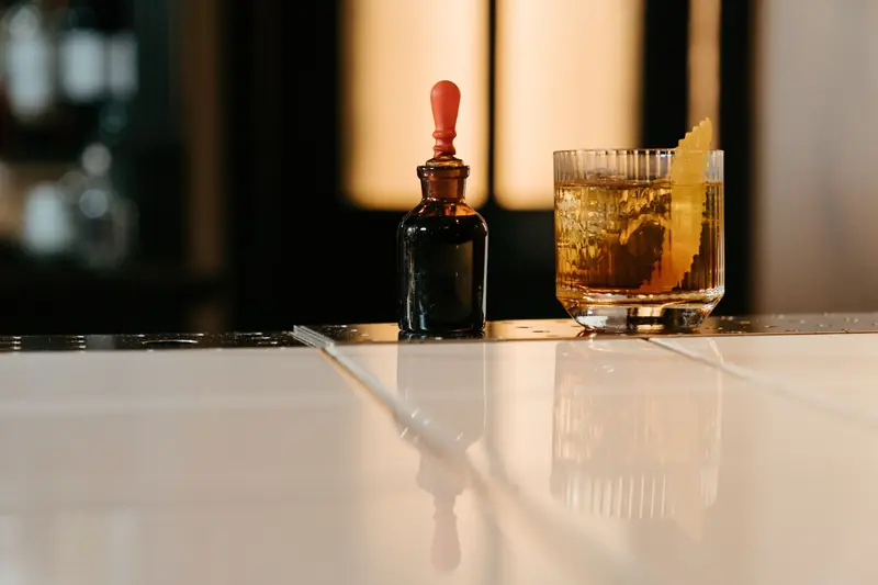 A stylish cocktail with bitters on a sleek bar counter featuring a citrus garnish