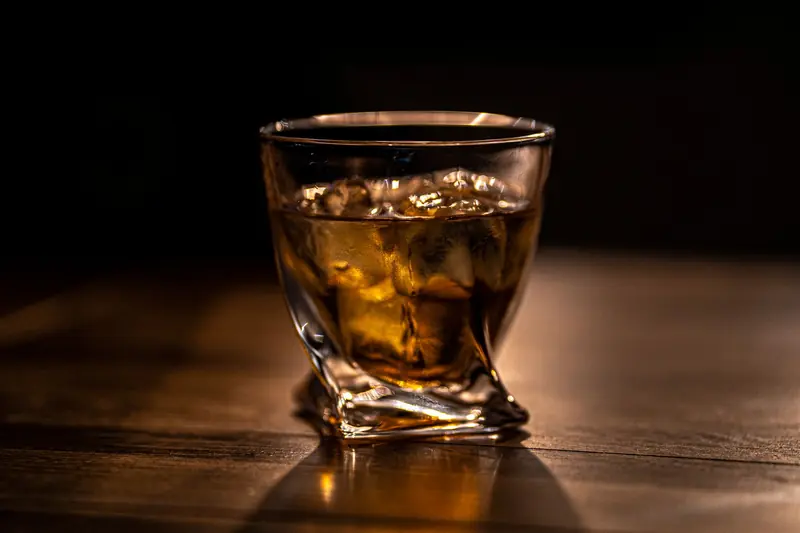 Close-up of whiskey on rocks in a stylish glass on a wooden table, creating a warm, sophisticated ambiance