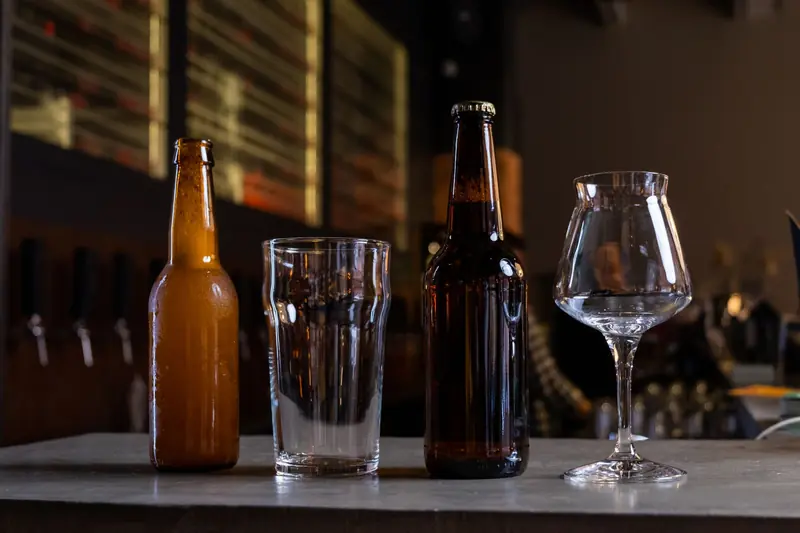 Close-up of craft beer bottles and glasses on a pub table, perfect for beverage themes