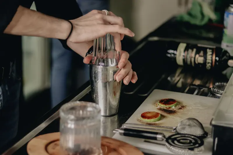 Close-up of a bartender using a shaker to mix a cocktail in a kitchen setting