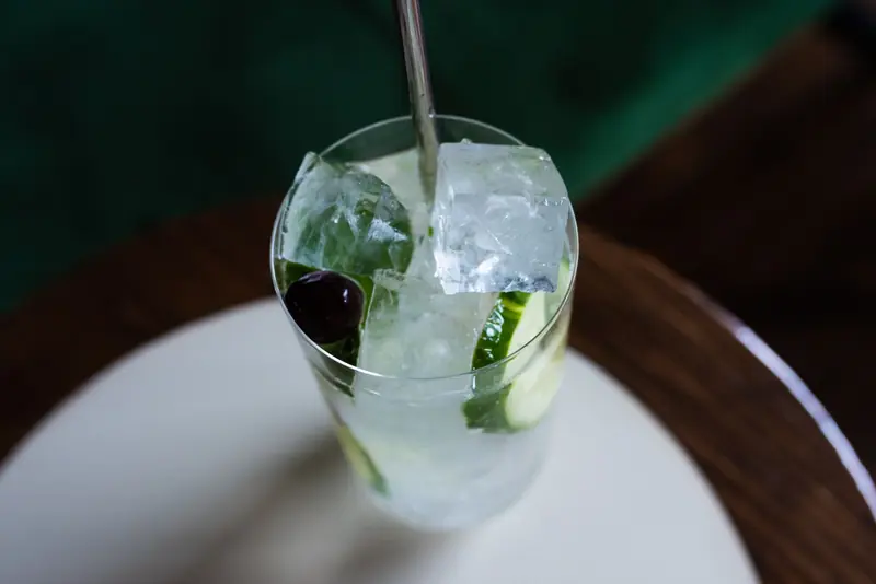 Top view of a refreshing gin cocktail with cucumber slices and ice cubes in a clear glass