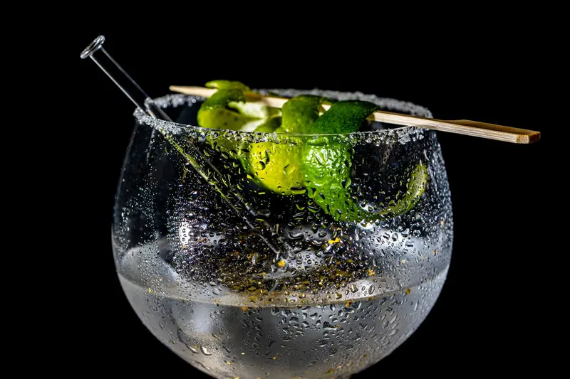 Close-up of a refreshing citrus cocktail with lime garnish on a black background