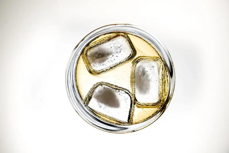 Top-down view of a chilled drink with ice cubes in a clear glass against a white background
