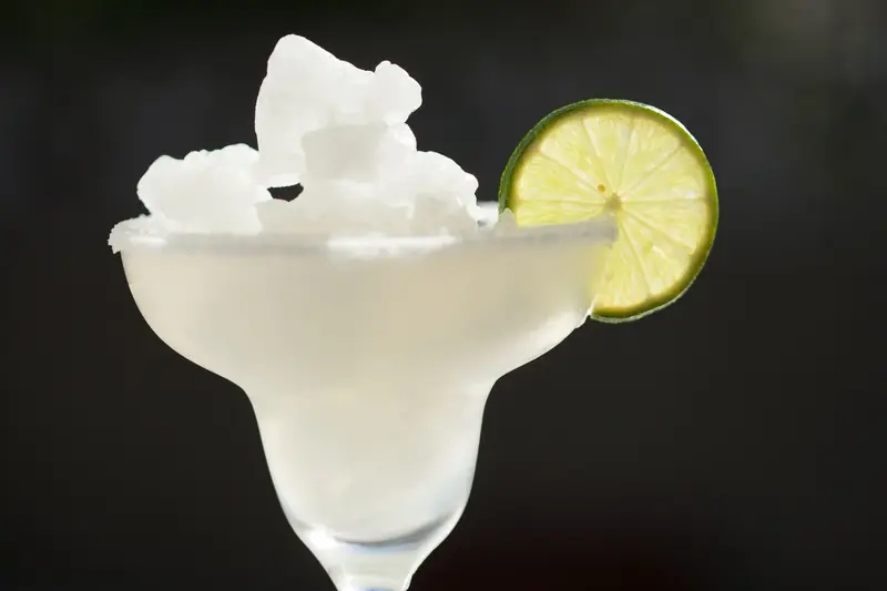 Close-up of a classic frozen margarita in a glass with lime garnish, perfect for summer refreshment