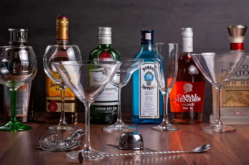 Assorted liquor bottles with cocktail glasses on a wooden surface - perfect for bar themes